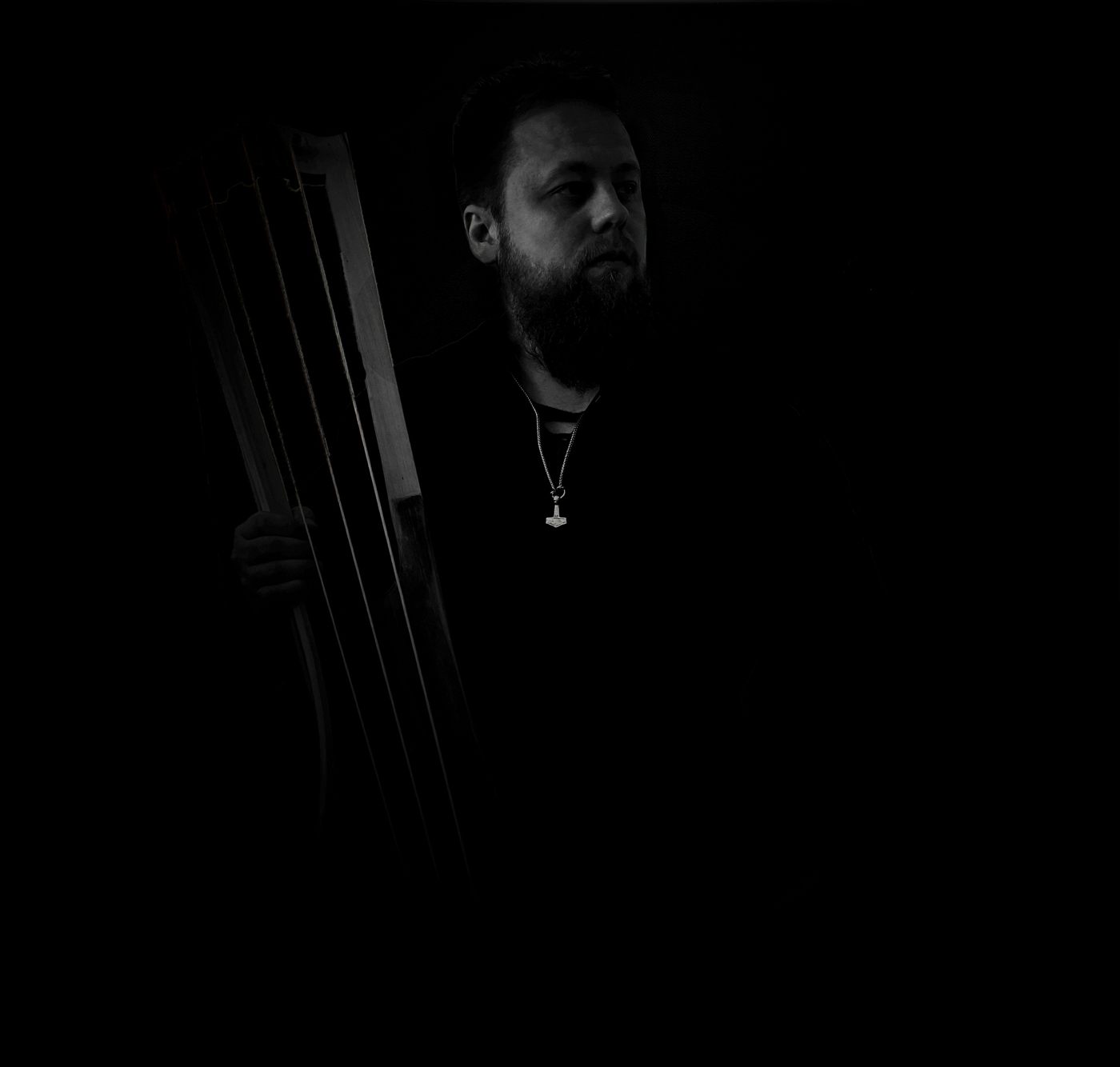 Danheim holding a jouhikko bowed lyre in near darkness
